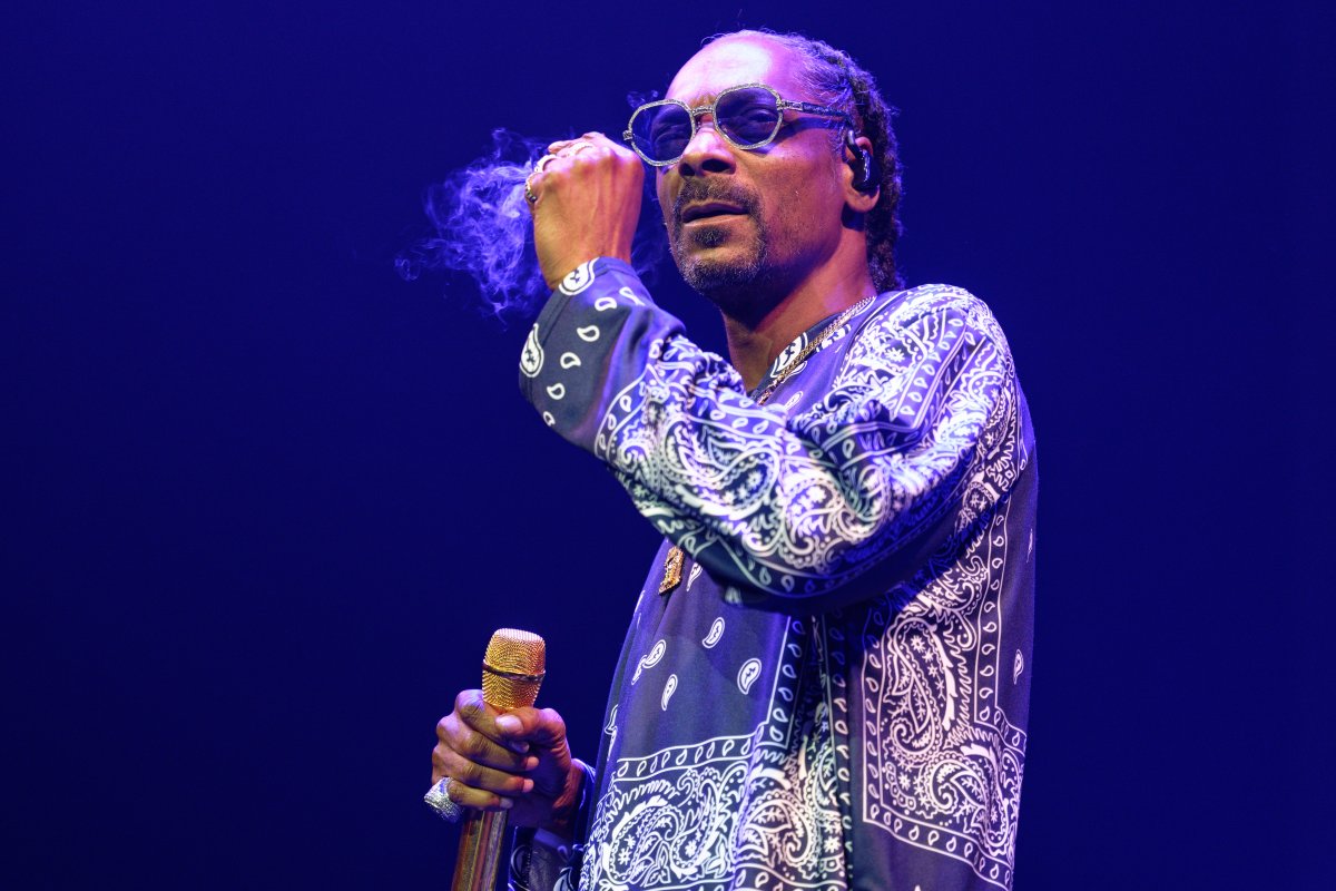 Snoop Dogg on stage. There is smoke around his hand.