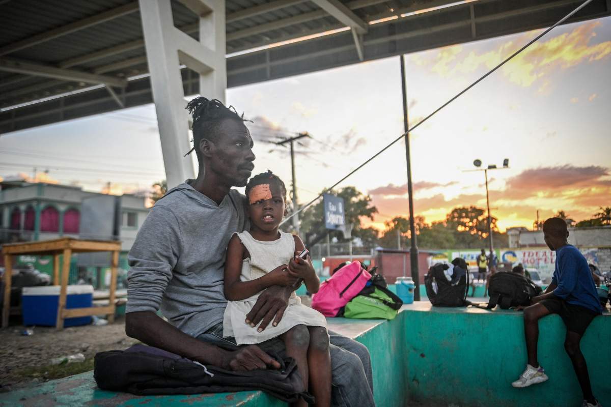 Exson holds his 6-year-old daughter, Francesca, who was injured during gang clashes, in a public square in the Port-au-Prince suburb of Clercine on November 15, 2023 after fleeing their home in Blanchard, Cite Soleil, Port-au-Prince, Haiti, when gang clashes broke out nearby. The Fontaine Hospital Center, the main hospital in Port-au-Prince’s largest shantytown, was completely evacuated on November 15 after violent gang clashes broke out at its gates.