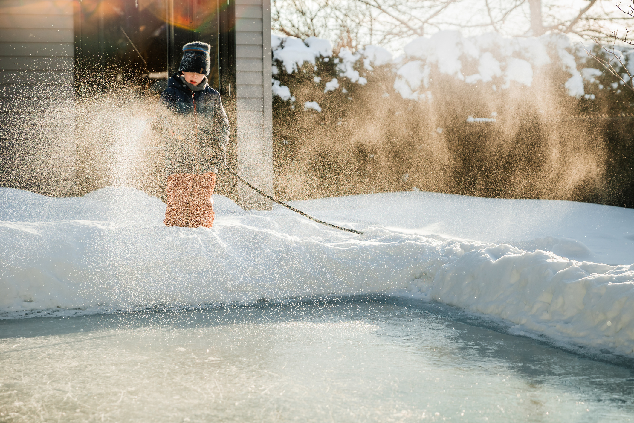 Kid sprays water on his backyard rink