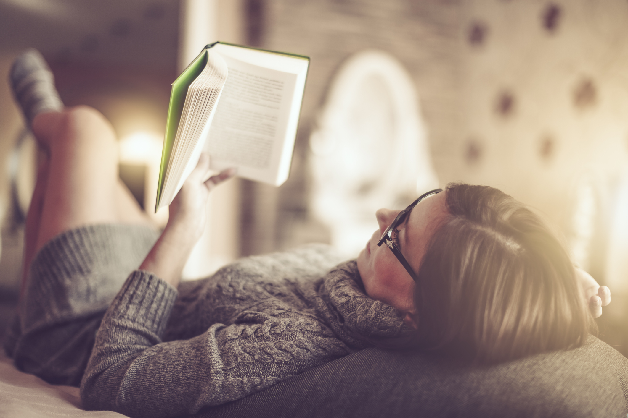 woman reads a book on a couch