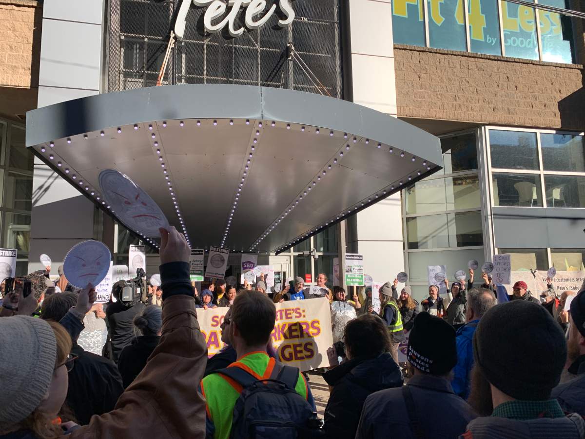 Striking Pete’s workers hold up an image of a nickel with a frown drawn onto the five-cent coin.