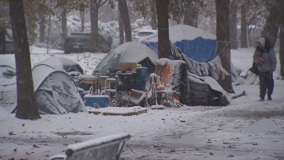 Someone walks by a tent camp in Halifax Wednesday during the year’s first snowfall.