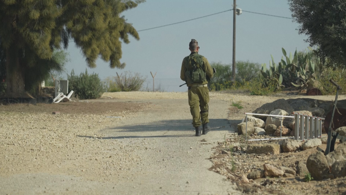 An Israeli defense force member walks down a dusty street.