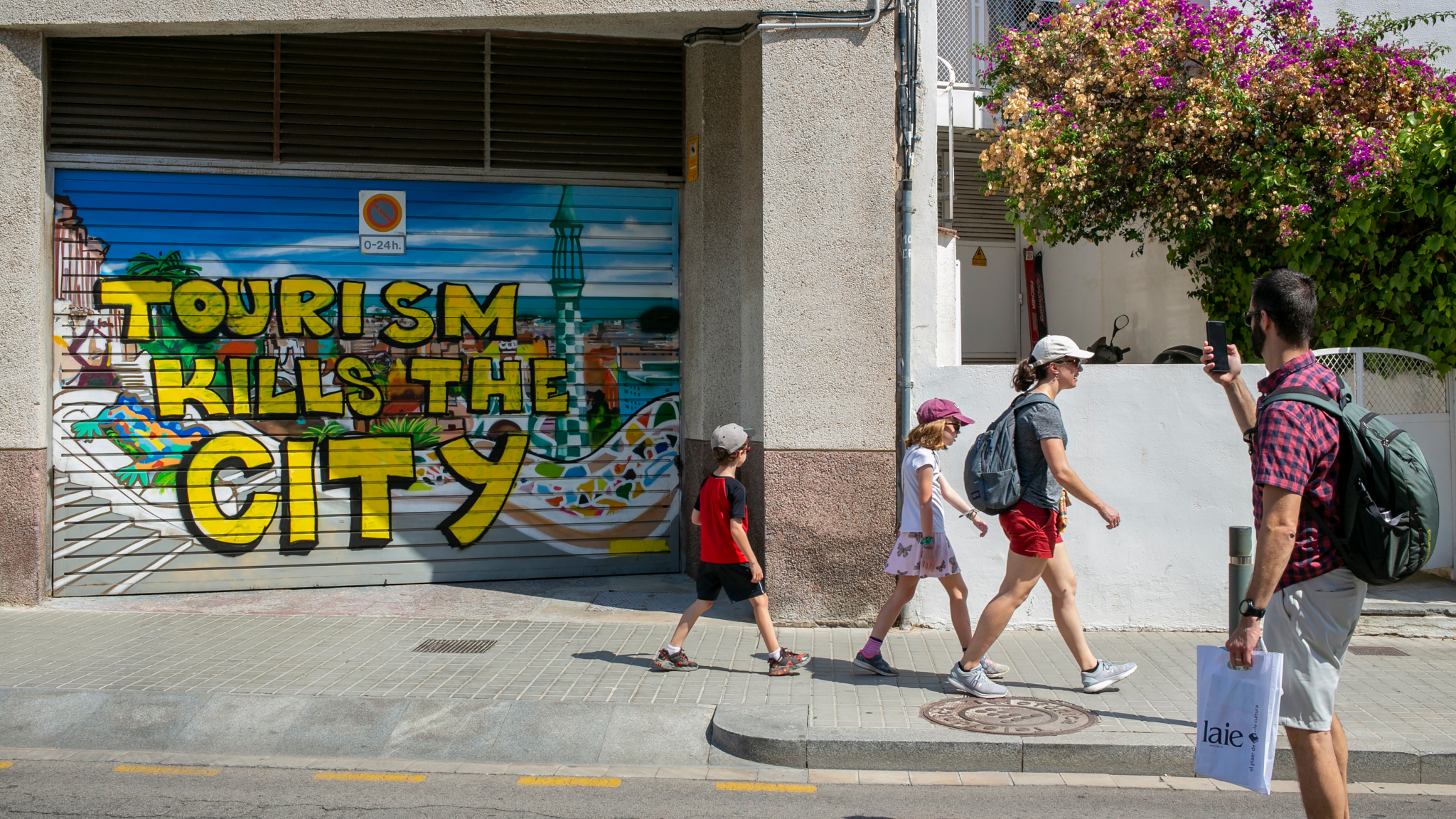 Tourists walk in front of graffiti against tourism on July 18, 2022, in Barcelona, Spain.