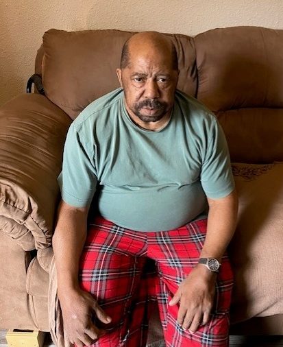 Randy Beals sitting on the sofa in the apartment that he shared with his partner before her passing. If his stepdaughter, Melissa, isn’t successful in an upcoming appeal in small claims court, he will be forced out of the unit.