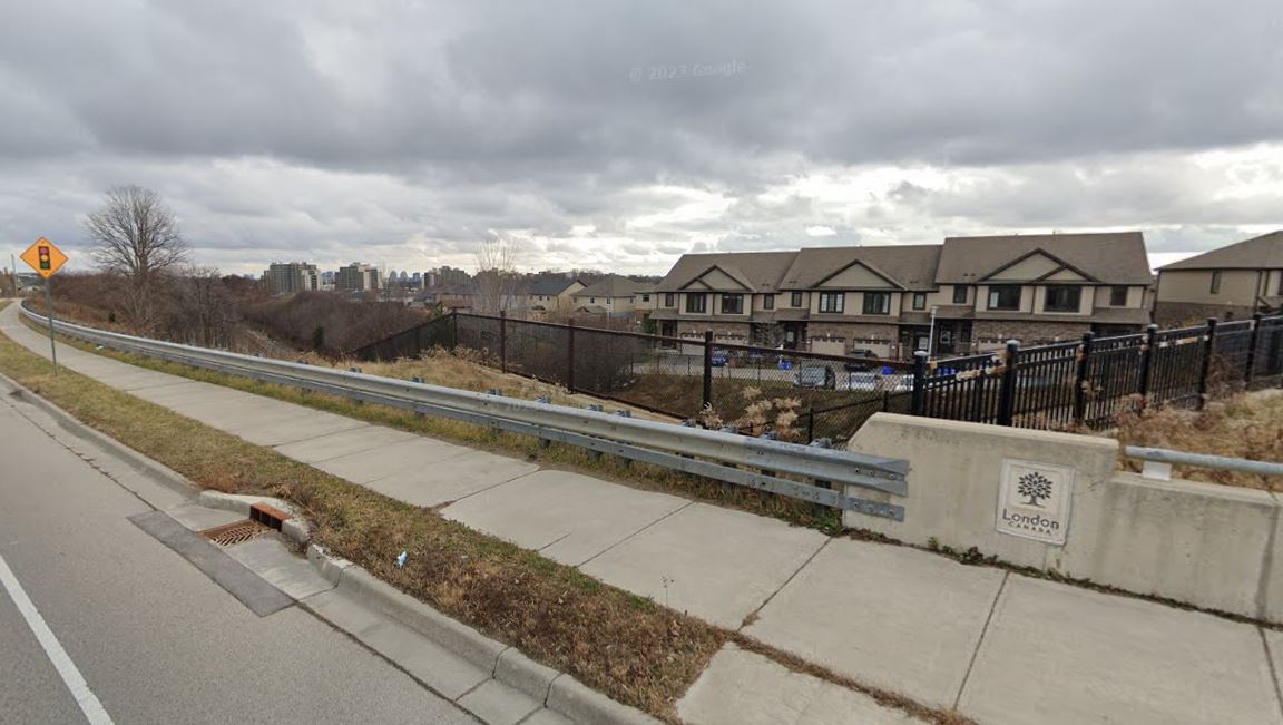 An overpass over a rail line overlooking a residential area.