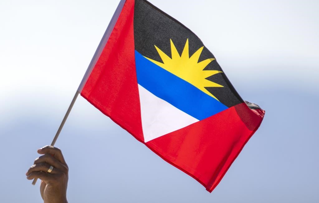 A person holds a flag of Antigua and Barbuda near Truth or Consequences, N.M., Thursday, Aug. 10, 2023. Two Canadians have died in Antigua, according to Global Affairs Canada. The department has not provided more information about the deaths that occurred in the Caribbean nation, citing privacy considerations.THE CANADIAN PRESS/AP, Andrés Leighton.