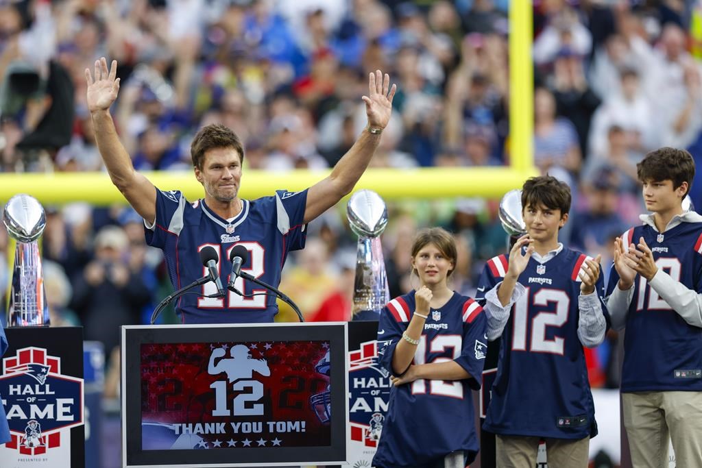 Former New England Patriots quarterback Tom Brady raises his arms after speaking while standing next to his daughter Vivian and sons Benjamin and Jack during the halftime ceremony of an NFL football game against the Philadelphia Eagles, Sunday, Sept. 10, 2023, in Foxborough, Mass.
