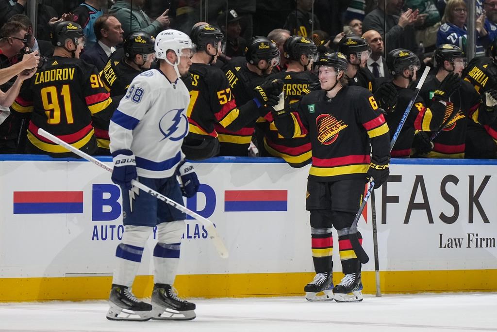 Vancouver Canucks’ Brock Boeser, back right, celebrates his second goal as Tampa Bay Lightning’s Mikhail Sergachev skates past during the game in Vancouver, on Dec. 12, 2023.