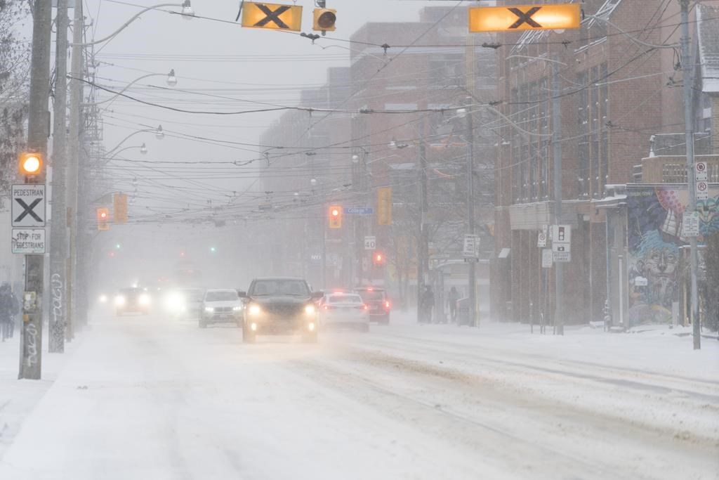 According to Environment Canada, Toronto has more snow and cold temperatures ahead. Cars drive through blowing snow during a snowstorm in Toronto on Friday, Dec. 23, 2022.