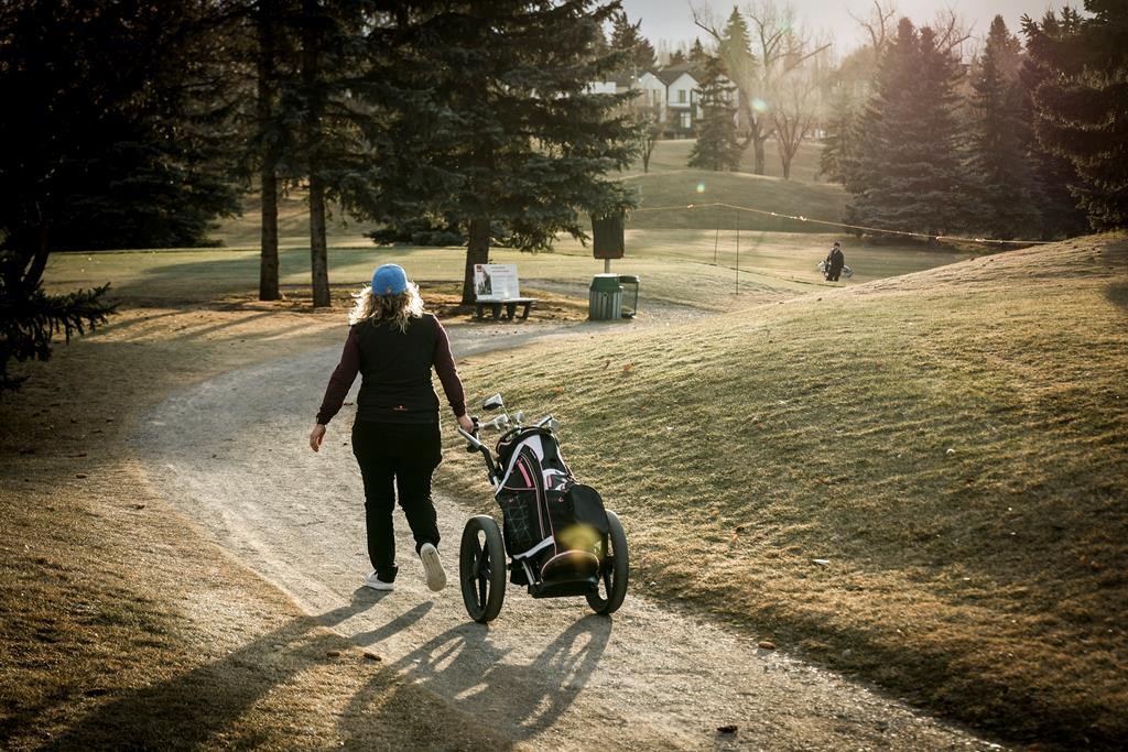 A golfer walks a cart path while playing a round at the Shaganappi Point golf course in Calgary on Tuesday, Dec. 5, 2023. THE CANADIAN PRESS/Jeff McIntosh