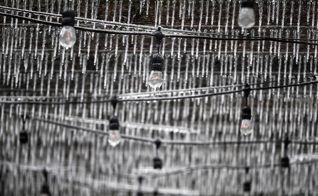Ice hangs from the light bulbs and wooden beams of a restaurant's outdoor patio as freezing rain falls in Ottawa, on Wednesday, April 5, 2023. 