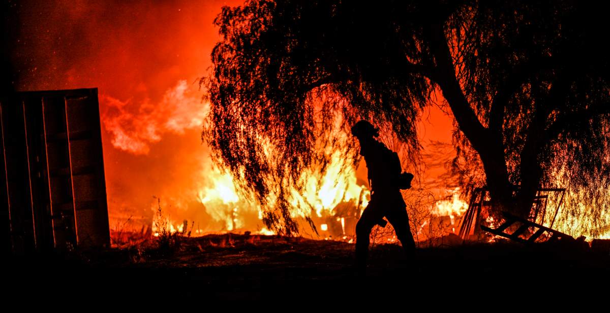 A photojournalist walks among the flames of a wildfire in rural Aguanga, Calif. Monday, Oct. 30, 2023. (Anjali Sharif-Paul/The Orange County Register via AP)