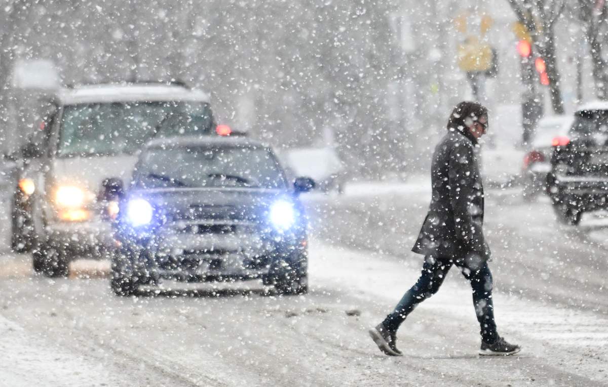 A person crosses a street during heavy snowfall in Montreal, Sunday, Dec. 3, 2023. Environment Canada has issued a weather warning as 15 to 20 cm of snow is expected for the region.