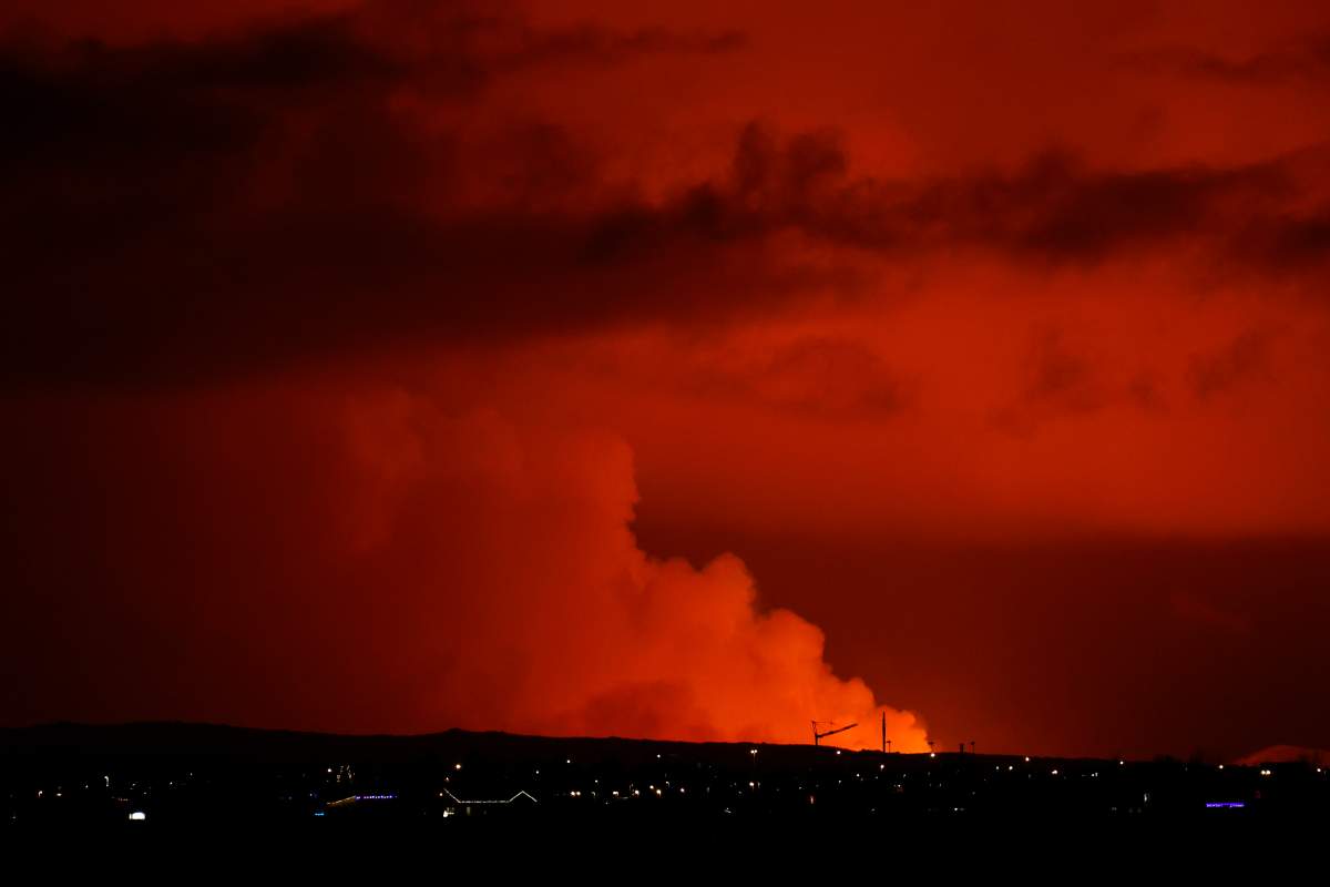 The night sky is illuminated caused by the eruption of a volcano on the Reykjanes peninsula of south-west Iceland seen from the capital city of Reykjavik, Monday Dec. 18, 2023. (AP Photo/Brynjar Gunnarsson)