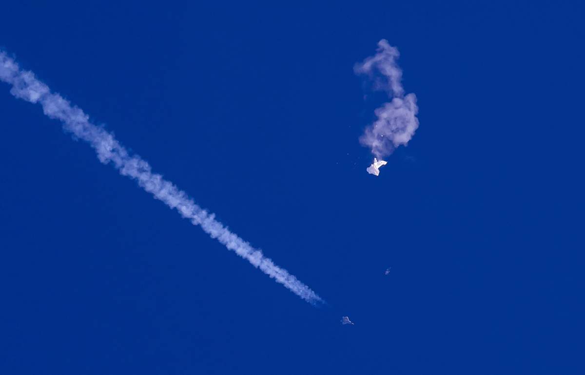 FILE – In this photo provided by Chad Fish, the remnants of a large balloon drift above the Atlantic Ocean, just off the coast of South Carolina, with a fighter jet and its contrail seen below it, Feb. 4, 2023. A missile fired on Feb. 5 by a U.S. F-22 off the Carolina coast ended the days-long flight of what the Biden administration says was a surveillance operation that took the Chinese balloon near U.S. military sites. It was an unprecedented incursion across U.S. territory for recent decades, and raised concerns among Americans about a possible escalation in spying and other challenges from rival China. (Chad Fish via AP, File)