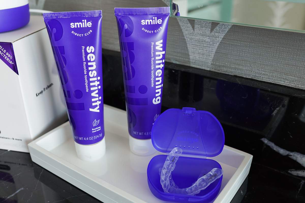 Two SmileDirectClub branded paste tubes and an aligner sit on a counter.