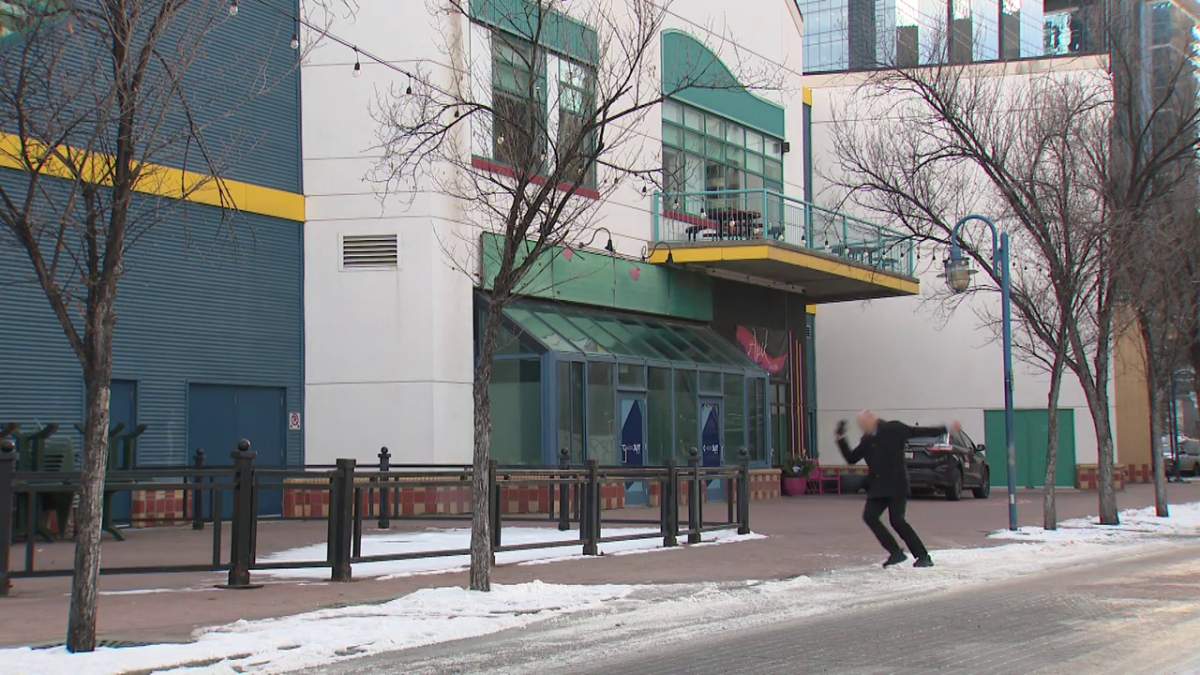 A man is seen slipping on ice in Calgary on Dec. 15, 2023.