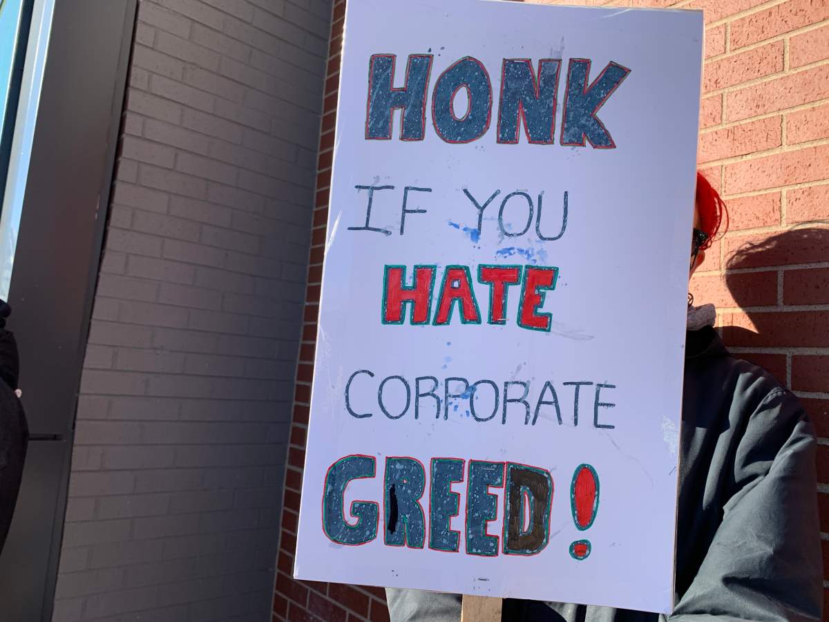 A sign that reads “Honk if you hate corporate greed” is held outside a Sobeys location in Halifax on Saturday.