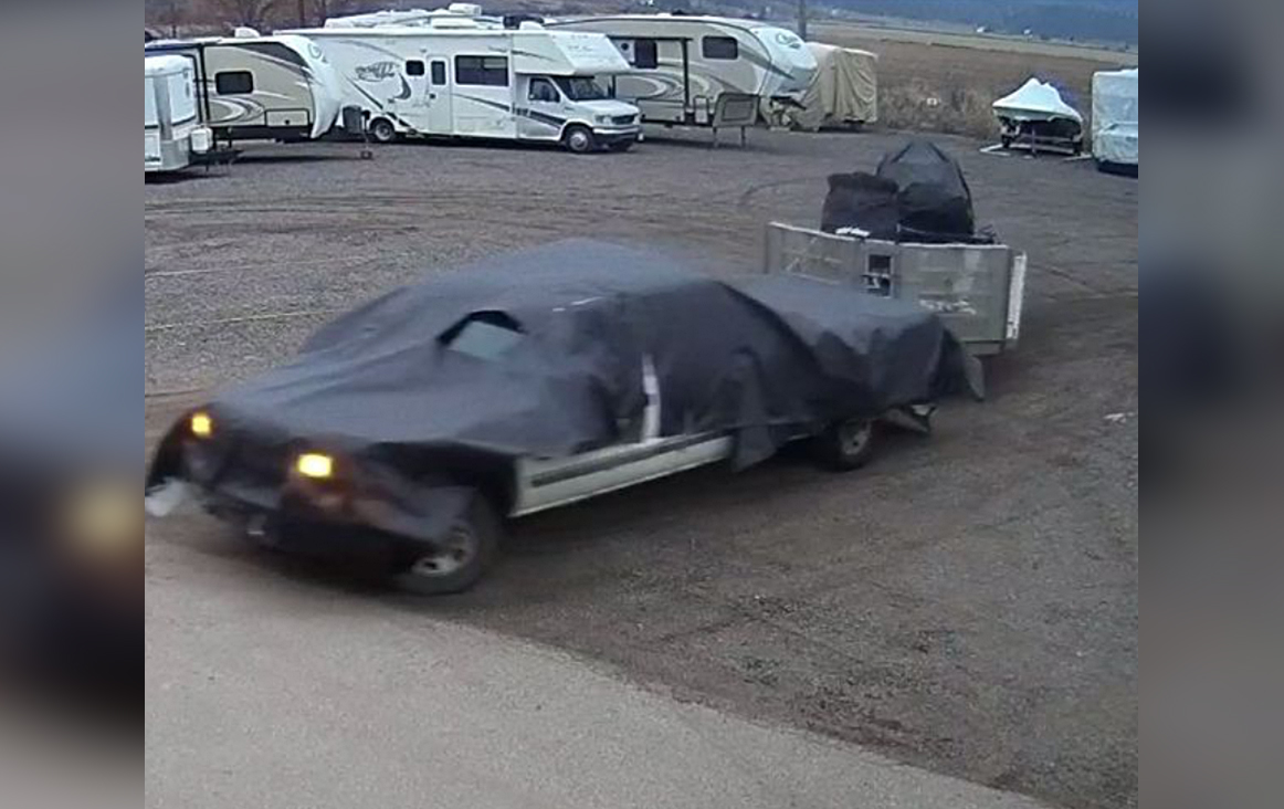A screenshot showing a white truck, covered with a black tarp, hauling away the two stolen trailers.