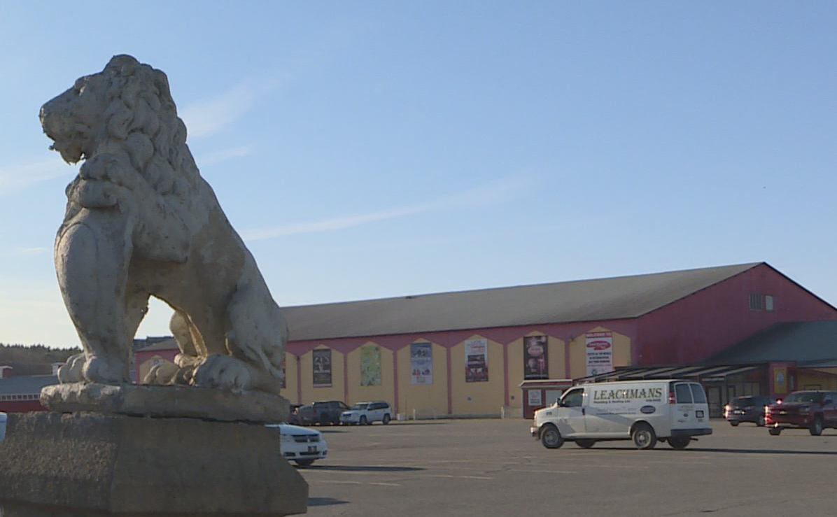 A lion statue in front of a parking lot and a yellow and red building.