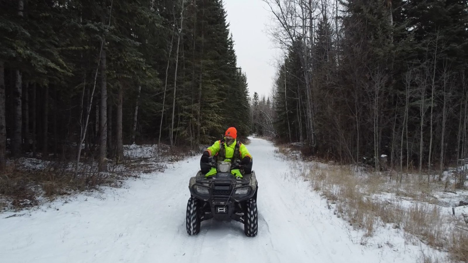 A man rides on an ATV in high vis.