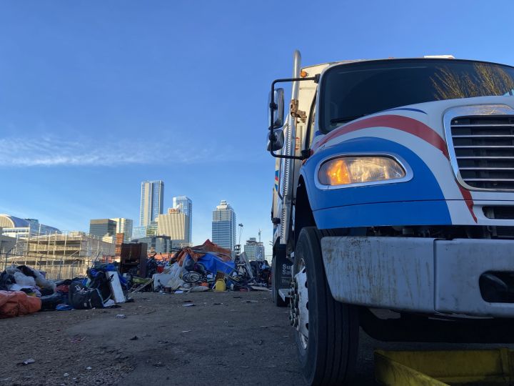 A garbage truck is seen at a central Edmonton homeless encampment on Dec. 29, 2023.