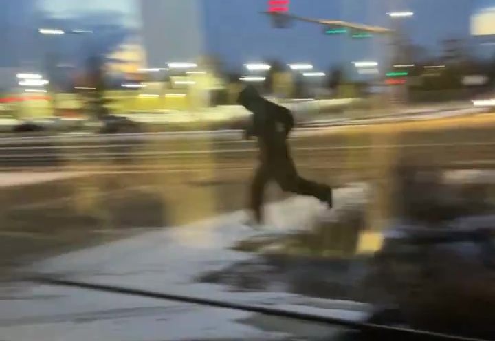 A man running away from a stolen car after it crashed into the Valley Line LRT train on 66 Street near the Whitemud Drive overpass on Monday, Dec. 4, 2023.