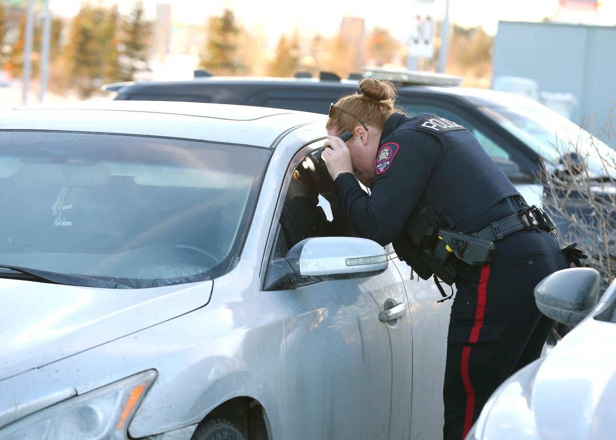 A Calgary Police Service member looks inside a vehicle with a bullet hole in the door panel on Christmas Day in the South Health Campus parking lot.