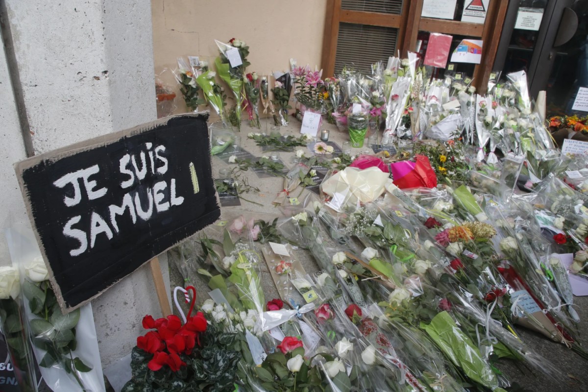 A poster reading "I am Samuel" and flowers lay outside the school where slain history teacher Samuel Paty was working on Oct. 17, 2020 in Conflans-Sainte-Honorine, northwest of Paris.