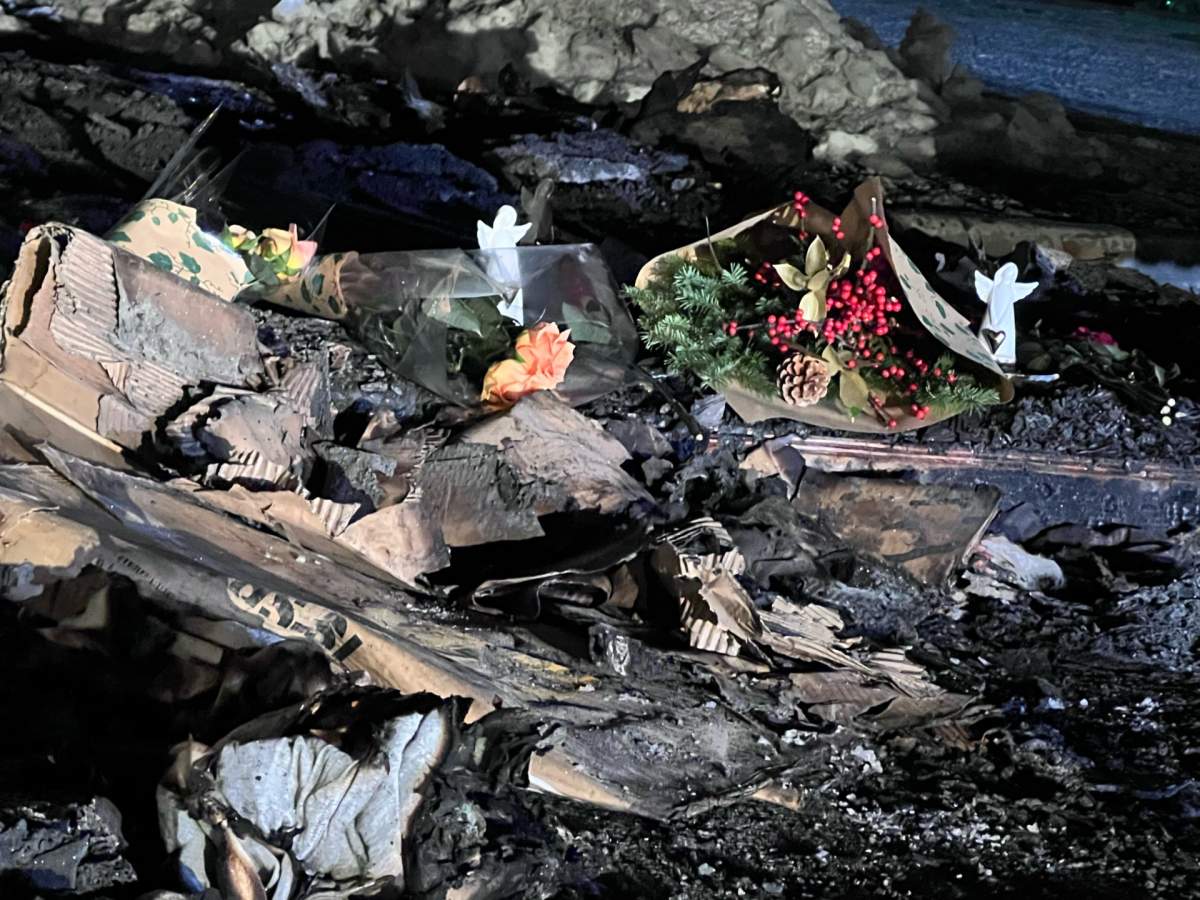 Bouquets are left at the scene of a shed fire near a home improvement store in Calgary on Dec. 11, 2023.
