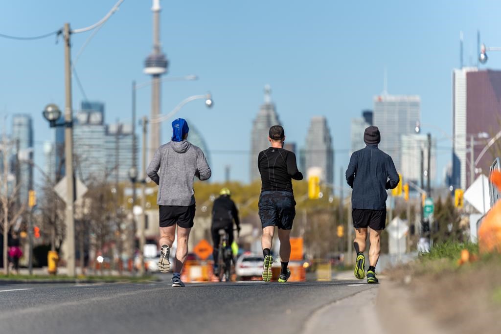 A battle has broken out over the sidewalks in Canada's most populous city. A group of runners run along Lake Shore Blvd. in Toronto on Saturday, May 1, 2021.