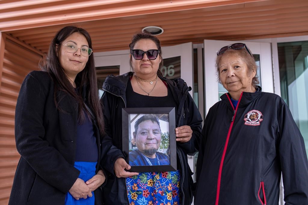 The family of Earl Burns: left to right, daughters Deborah Burns and Vanessa Burns and his wife, Joyce Burns, hold a photograph of Earl following a Saskatchewan RCMP preliminary timeline presentation in April 2023. THE CANADIAN PRESS/Liam Richards