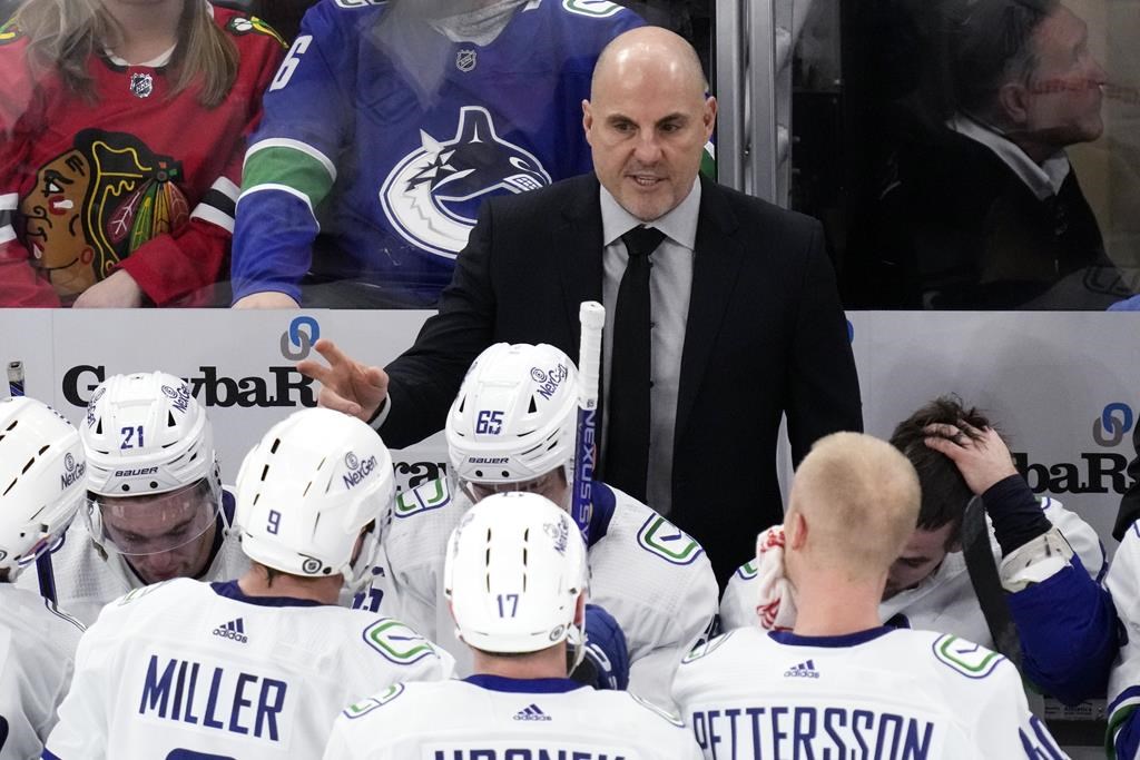 Vancouver Canucks head coach Rick Tocchet, top, talks to players during the third period of an NHL hockey game against the Chicago Blackhawks in Chicago on Dec. 17, 2023. Rick Tocchet took over the Vancouver Canucks a year ago, with the team struggling to find consistency in how it played, combined with wins.
