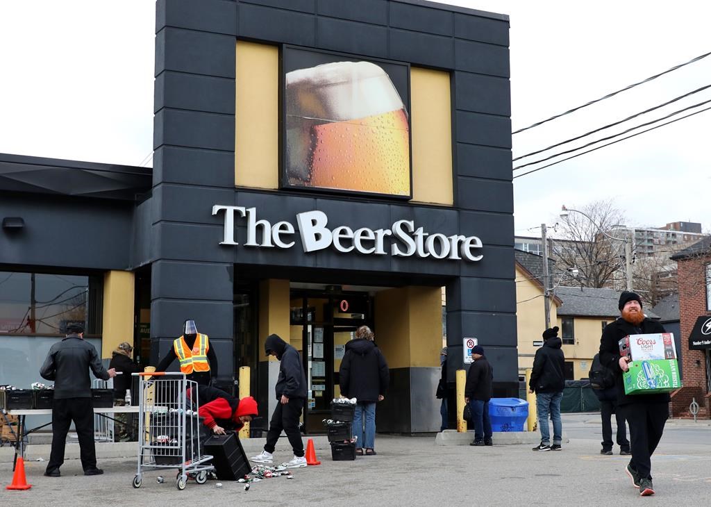 People line up in a parking lot for a long wait to return empties or buy beer at a Beer Store in downtown Toronto on Thursday, April 16, 2020. The Beer Store says it is expanding a delivery partnership with DoorDash Canada. THE CANADIAN PRESS/Colin Perkel.