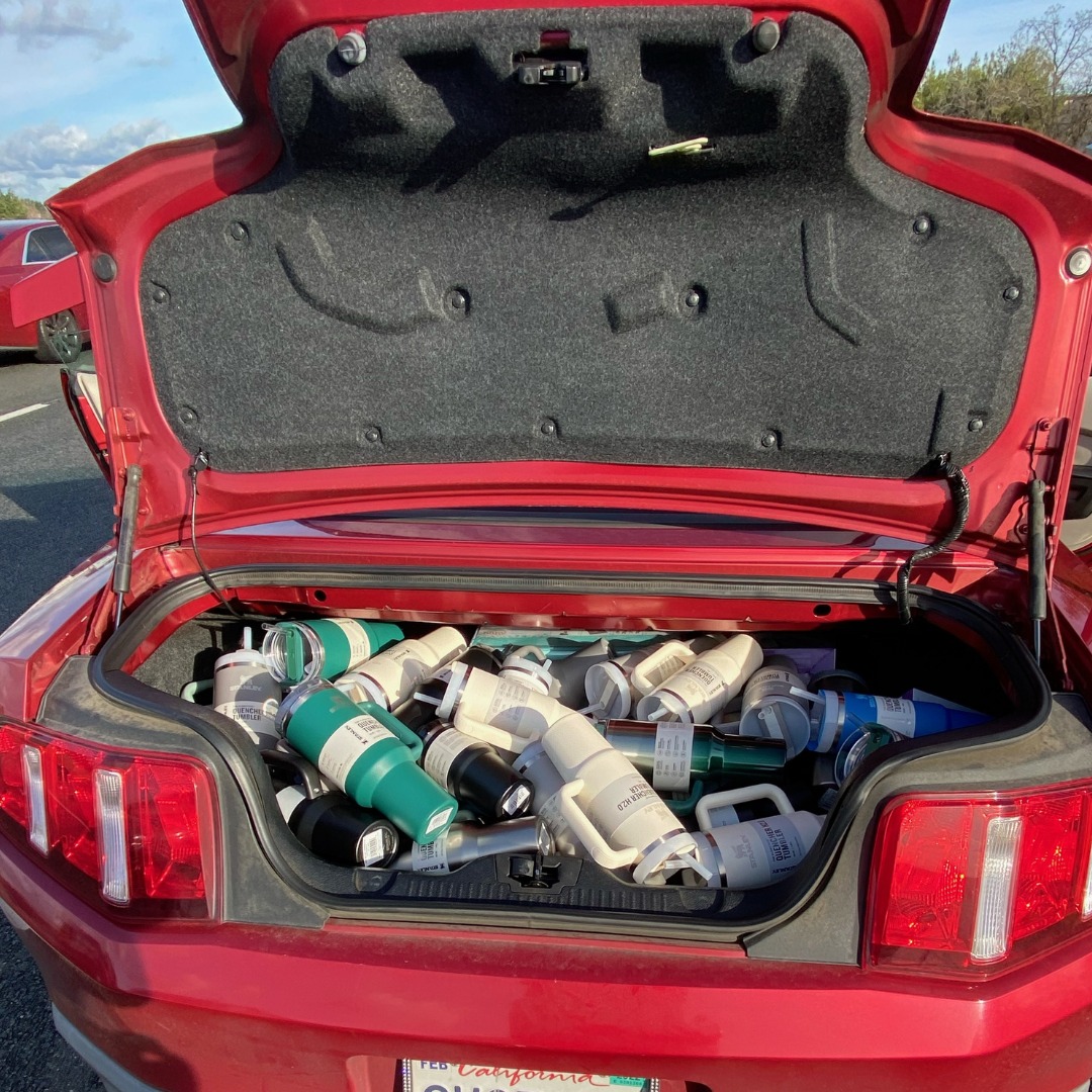 Dozens of Stanley water bottles crammed into the trunk of a car.