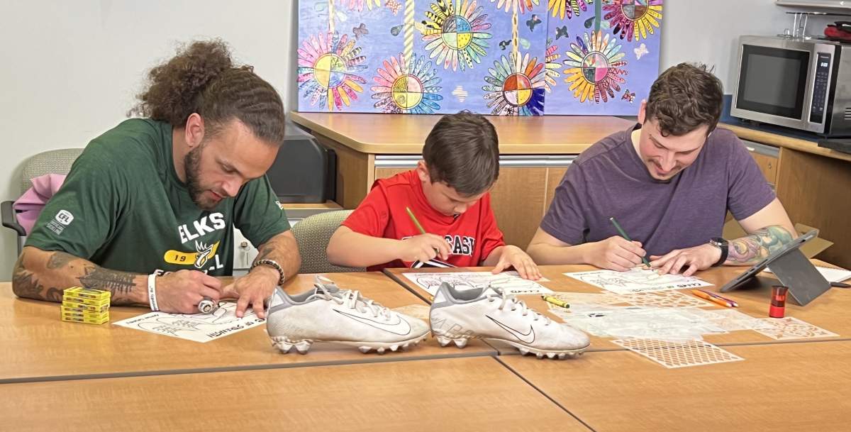 Two Edmonton Elks and a child design a shoe.