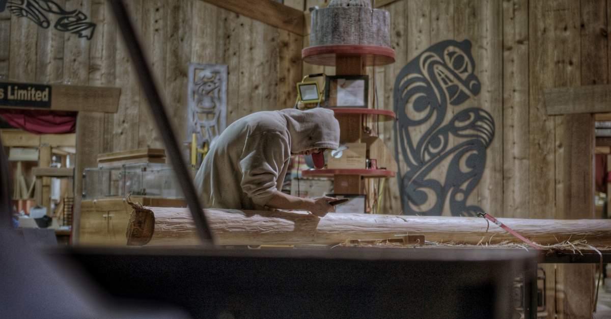A person carves a post that will be used as a repository