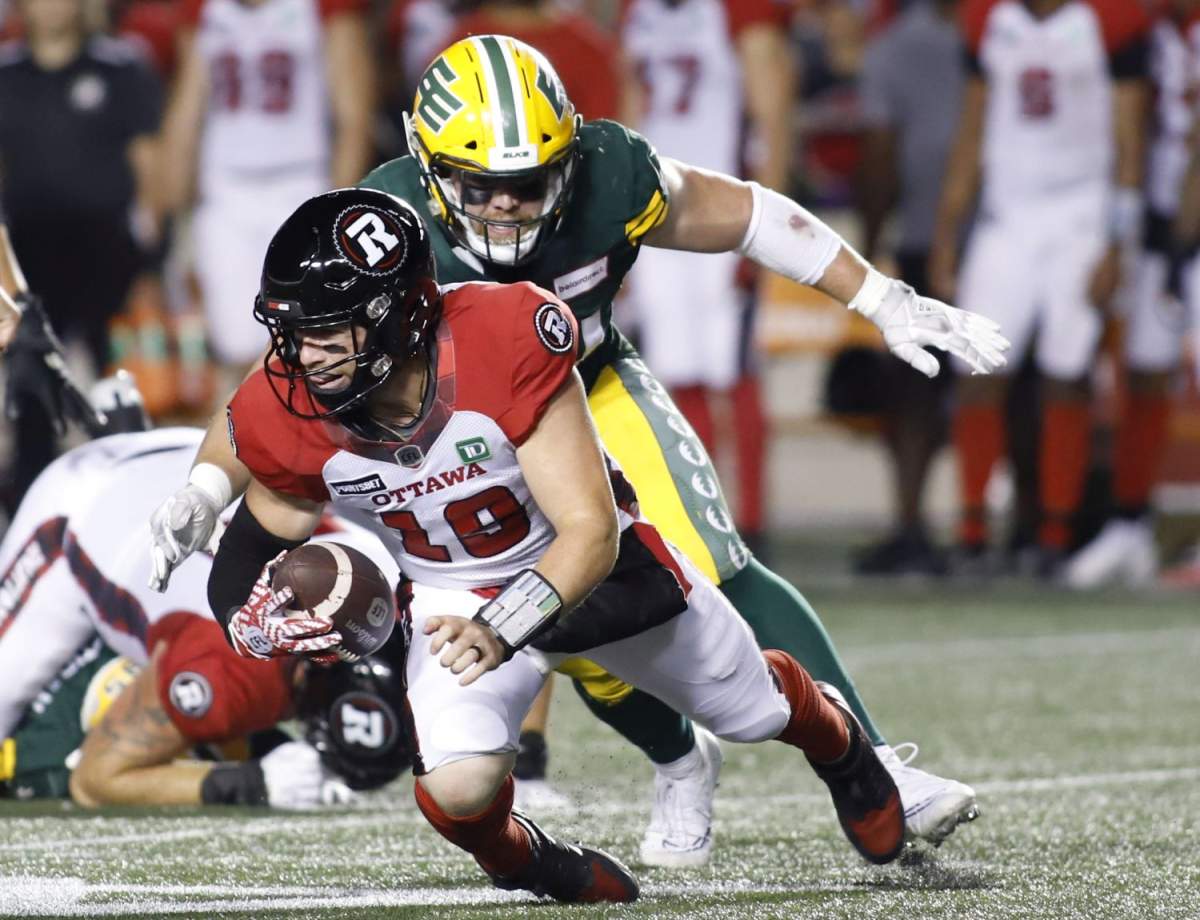 Ottawa Redblacks quarterback Nick Arbuckle (19) is sacked by Edmonton Elks Jake Ceresna (94) during second half CFL action in Ottawa on Friday, August 19, 2022.
