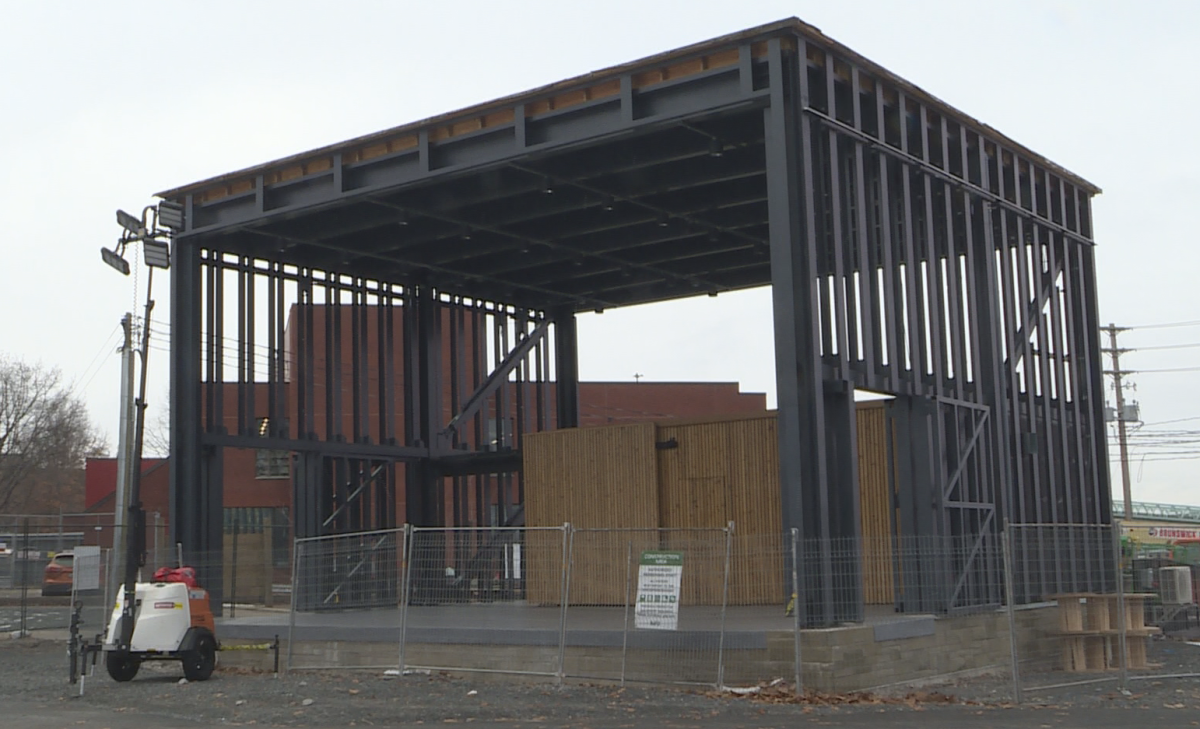 A black metal structure with wooden boards on the stage. It has a fence around it with a construction sign on it.