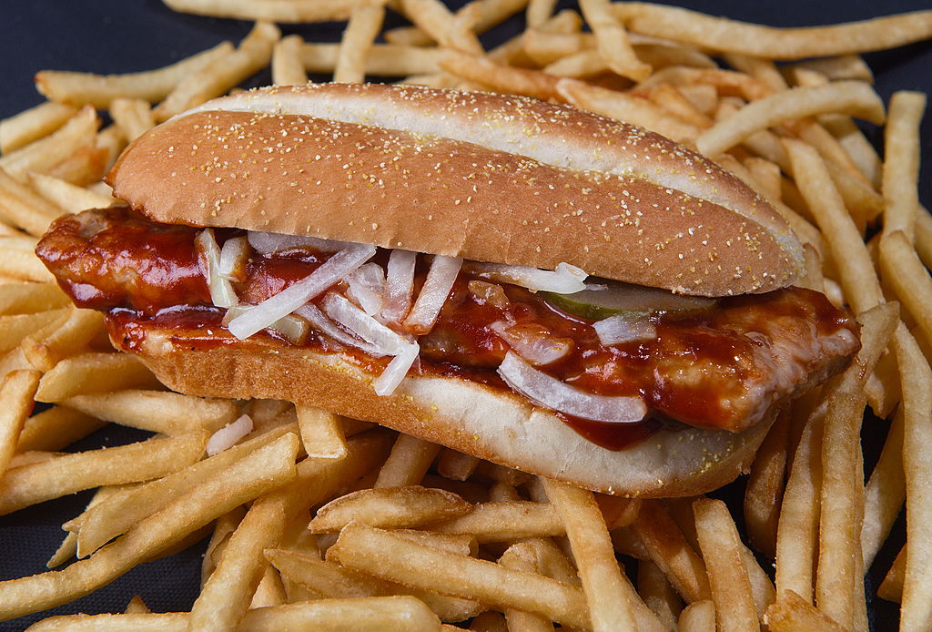 The McRib is pictured sitting on top of a bed of french fries.
