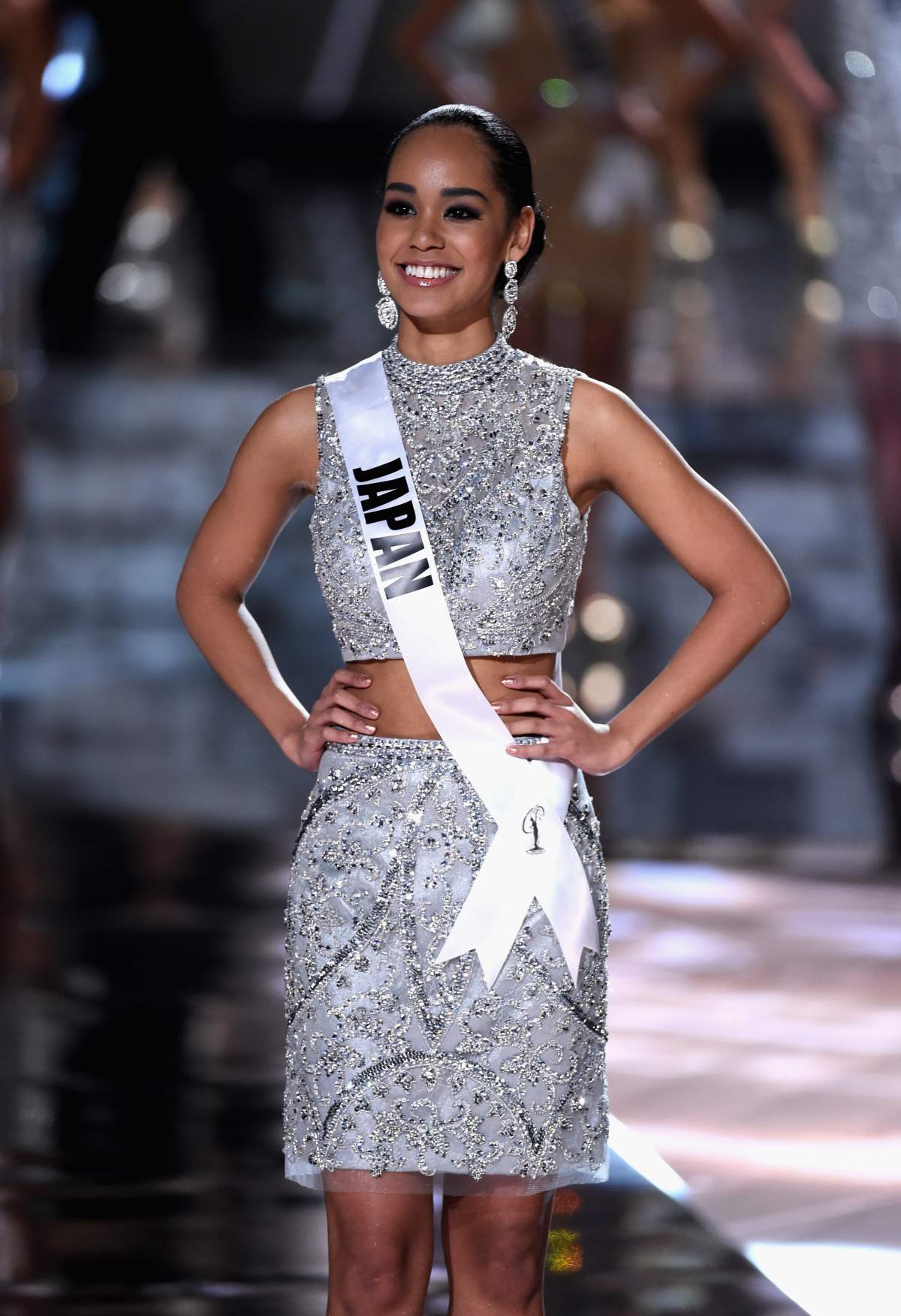 Ariana Miyamoto in a silver two-piece mini dress. Her white sash reads 'Japan.'
