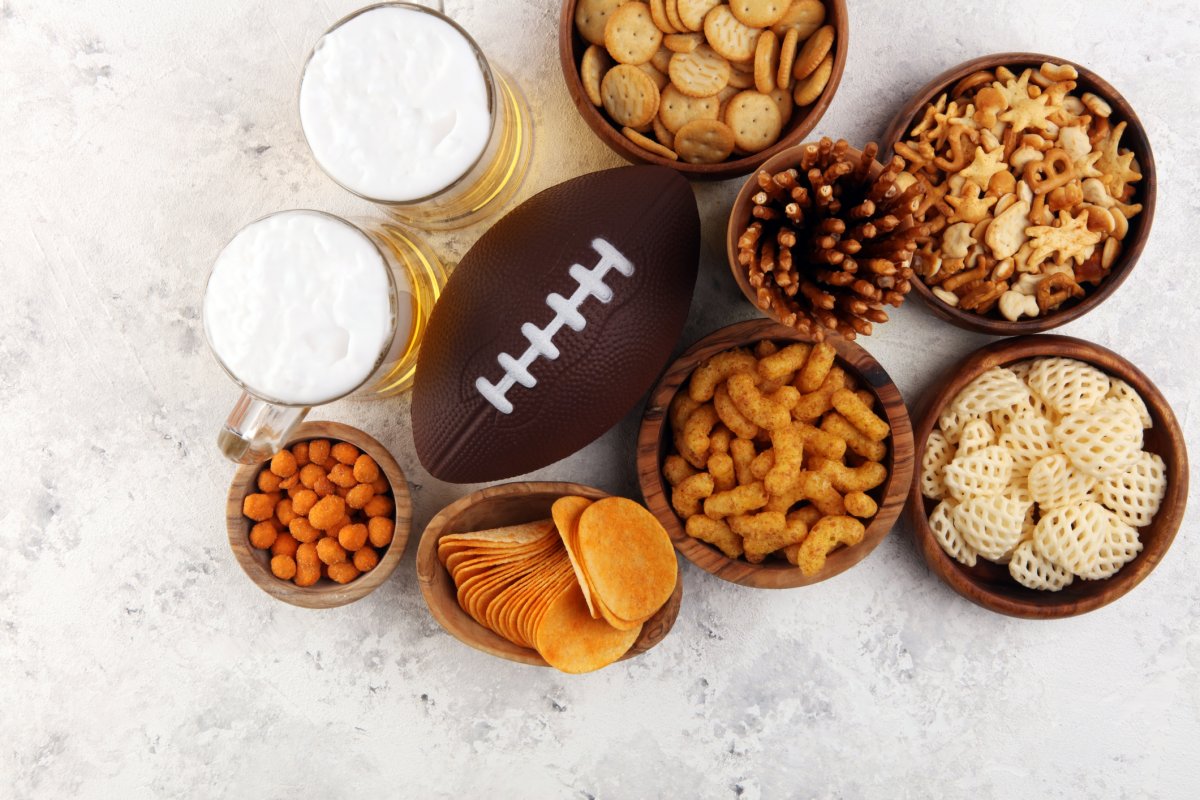 Chips, salty snacks, football and Beer on a table.