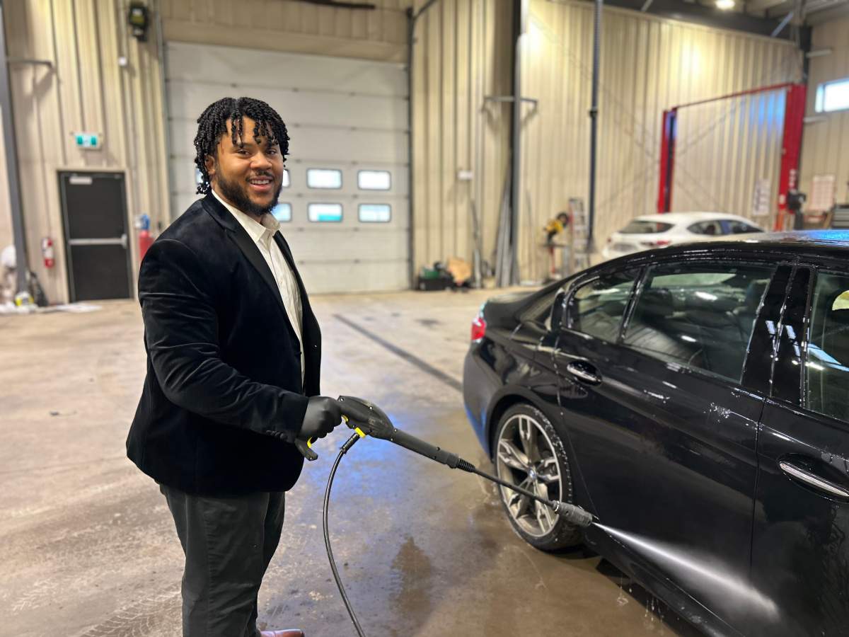Revello Smith smiles as he sprays down a vehicle inside his new shop on Windmill Road in Dartmouth.