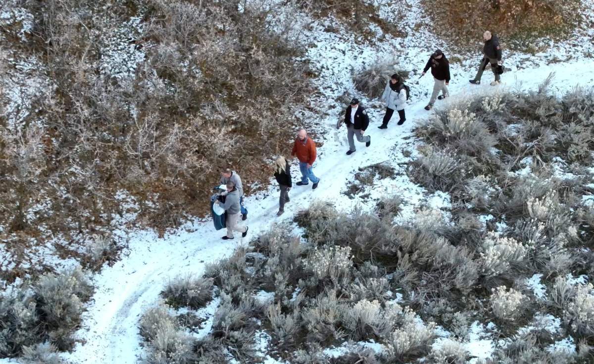 People walk single-file along a snowy path.