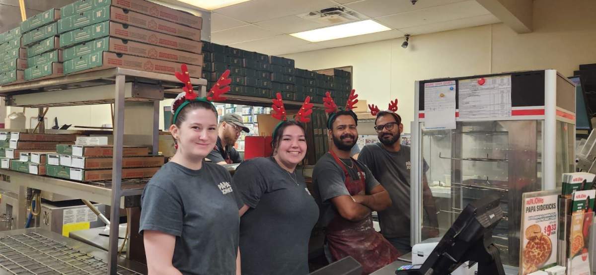 Staff at the Papa John's restaurant in Fredericton, N.B. pose for a photo just before Christmas . Harwinder Singh, who is shown third from the left, was killed in a single-vehicle crash on Boxing Day.