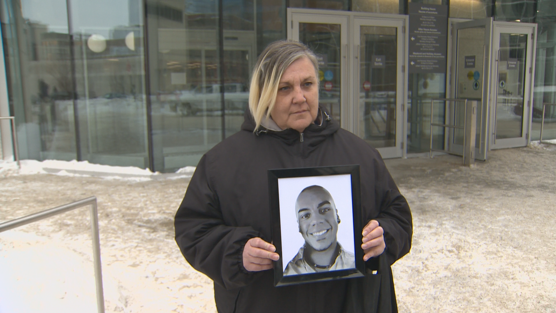 Tania Cayer holds a photo of her son, Tyree, outside of court on Tuesday, January 23, 2024. Tyree was killed in a stabbing attack at the Millennium Library in December 2022.