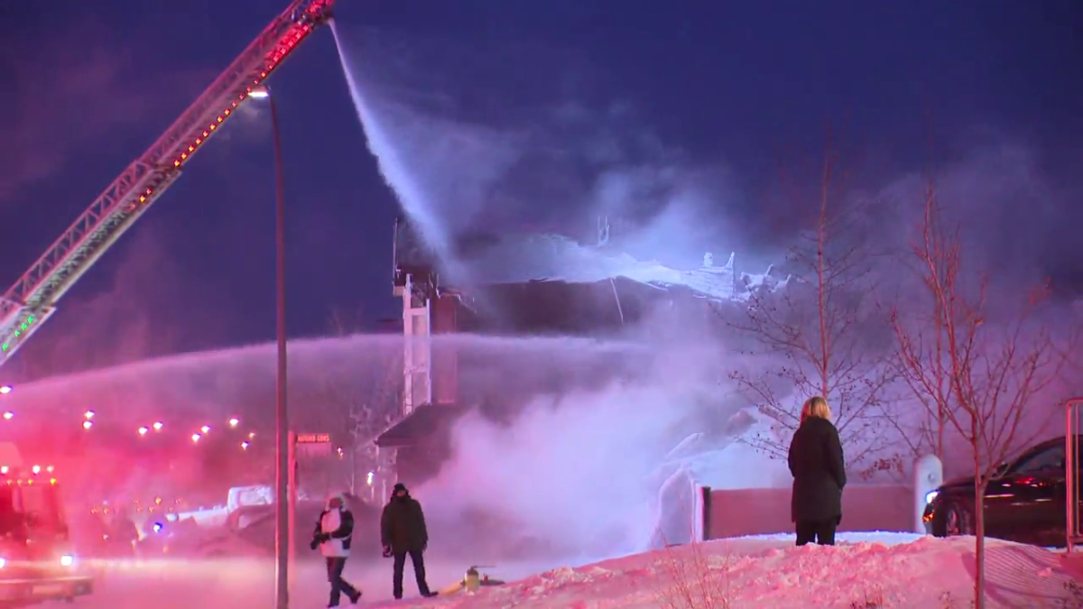 Calgary Fire Department crews fight a house fire in Auburn Bay on Jan. 11, 2024, as people look on.