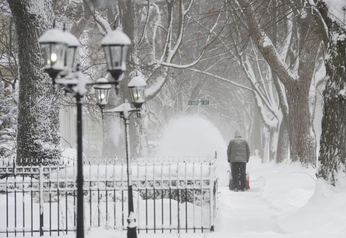 A man clears snow along a sidewalk on State Street in St. Joseph, Mich., Monday, Jan. 15, 2024. Residents are digging out after a winter storm moved across the state with blowing and drifting snow and temperatures in the single digits. (Don Campbell/The Herald-Palladium via AP)