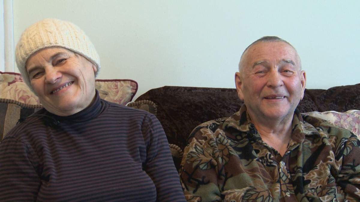 An elderly man and woman sit together on a couch.